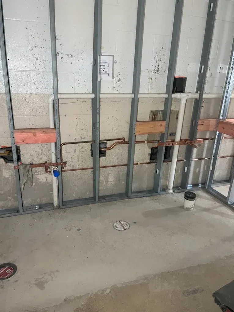 Exposed wall framing with electrical boxes and wiring in an unfinished interior room.