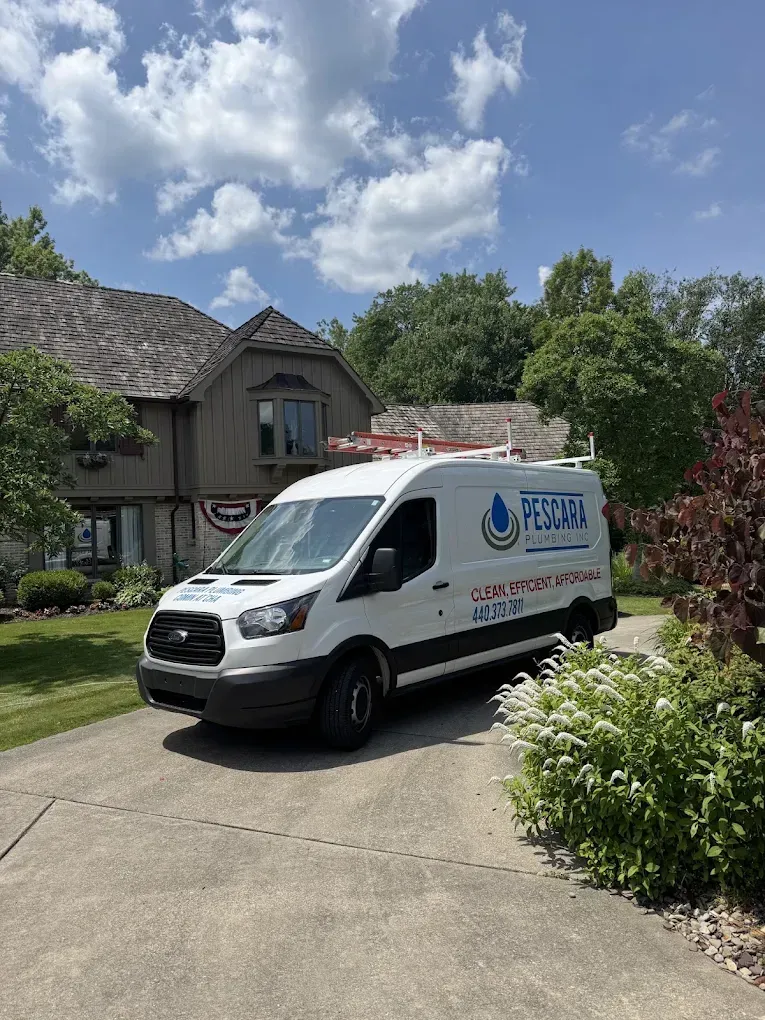 White service van parked in a driveway beside a house and garden on a sunny day