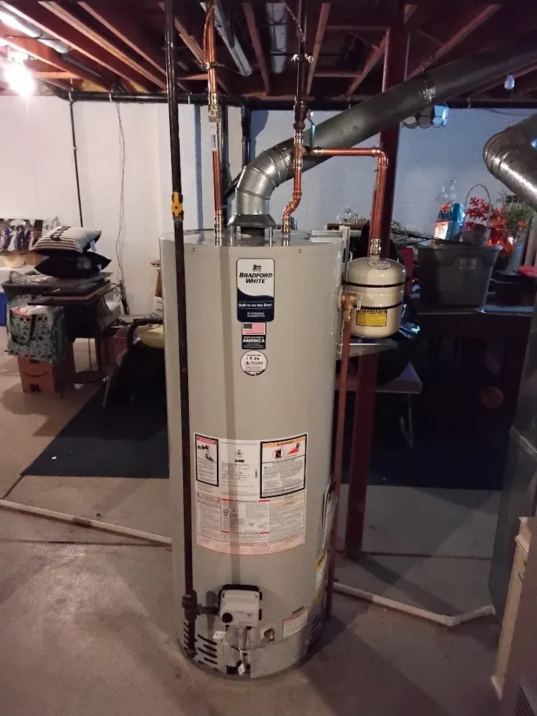 Water heater with vent pipe in a basement utility room.