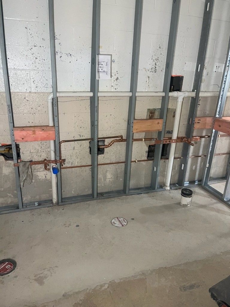 Exposed wall framing with metal studs and electrical boxes behind a concrete floor in a renovation space