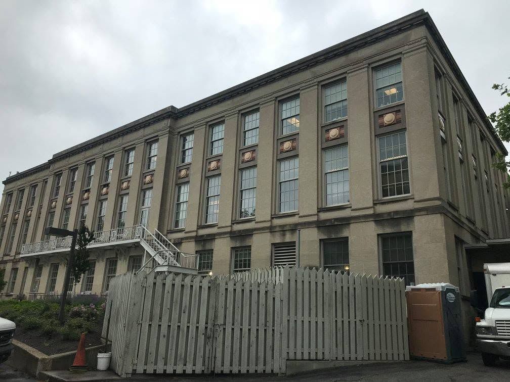 Large gray stone building with tall windows and a fenced foreground