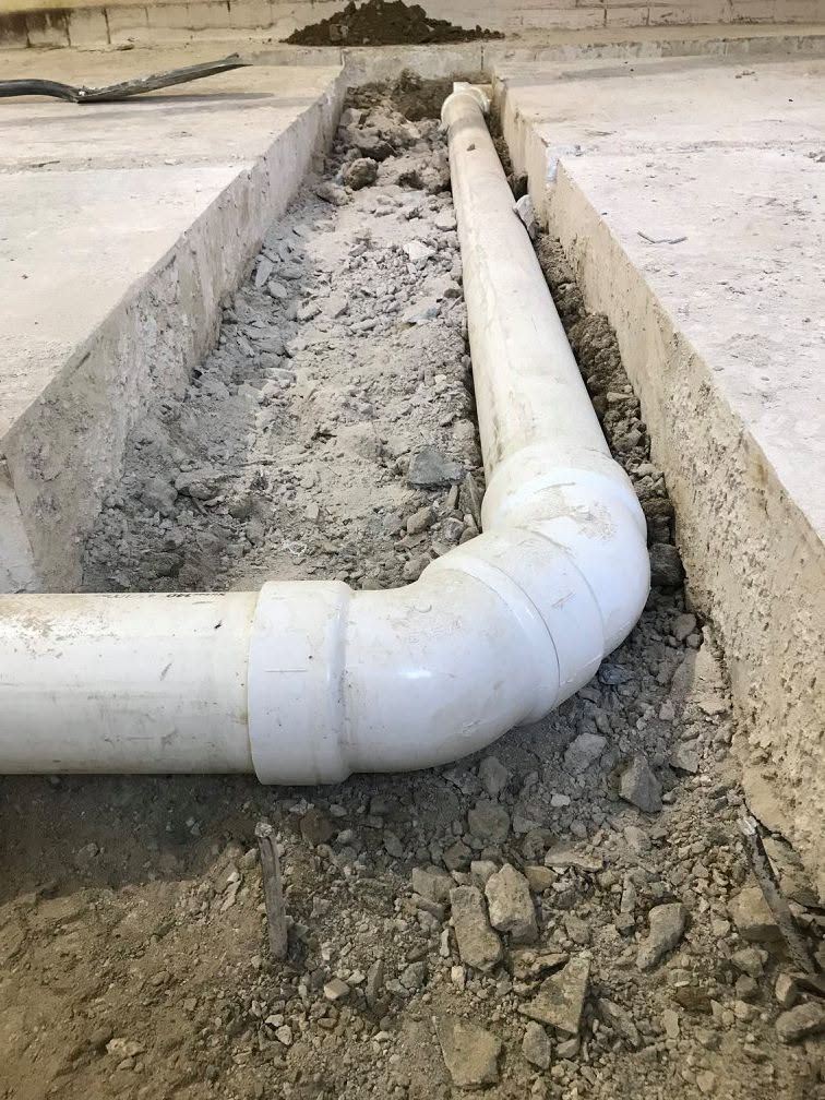 White PVC pipe elbow in a concrete trench at a construction site