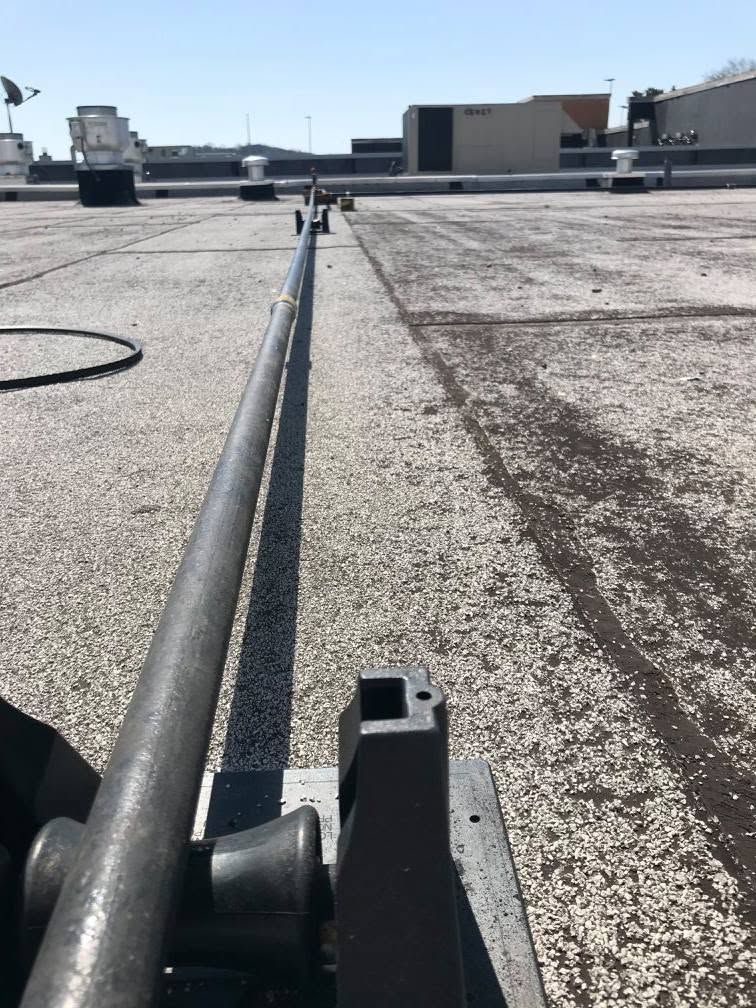 Rooftop gravel surface with a black pipe or cable running along the center under a bright sky