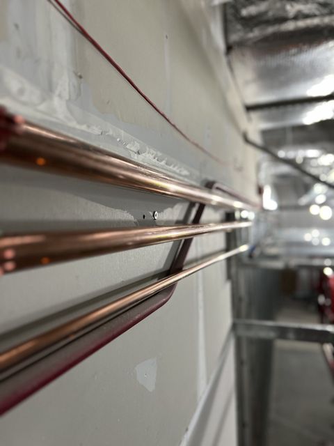 Copper pipes running along a wall in an industrial hallway or utility space