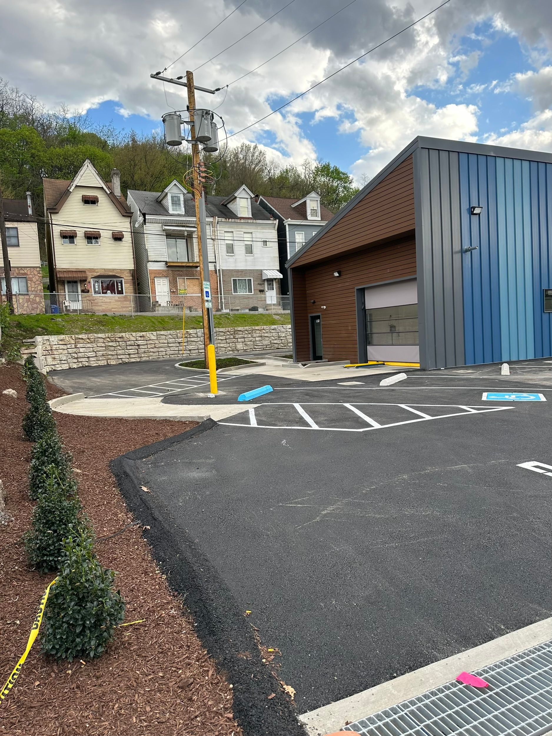 A parking lot with a blue building in the background and a brick building in the background.