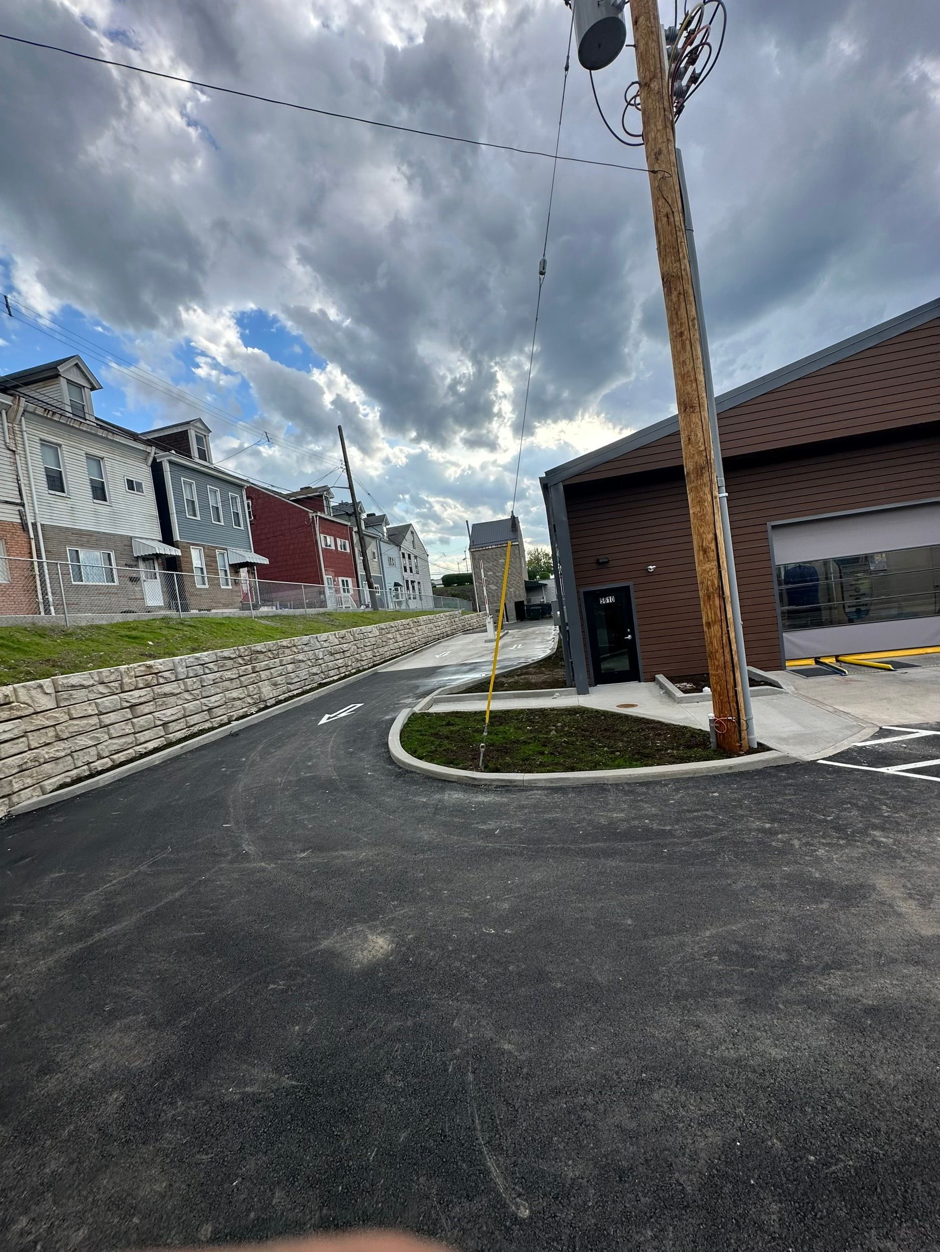 A telephone pole is in the middle of a street next to a building.