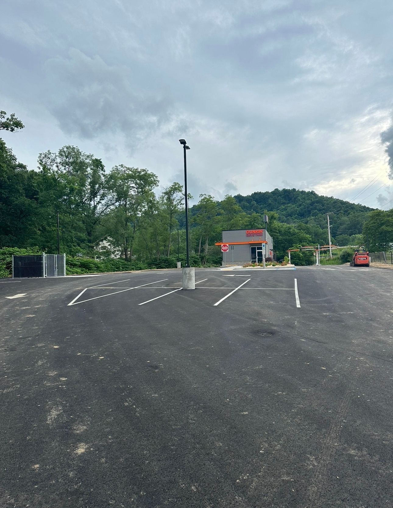 A parking lot with a building in the background and a mountain in the background.