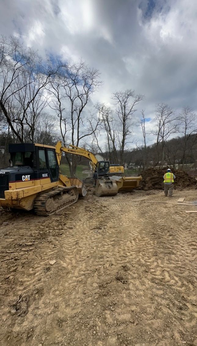 A group of construction vehicles are parked in a dirt field.
