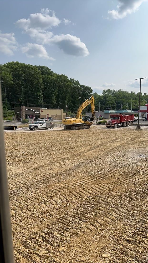 A large yellow excavator is driving through a dirt field.