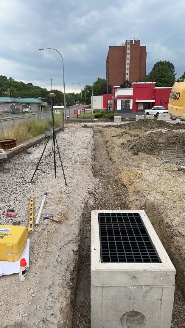 A construction site with a building in the background and a concrete box in the foreground.