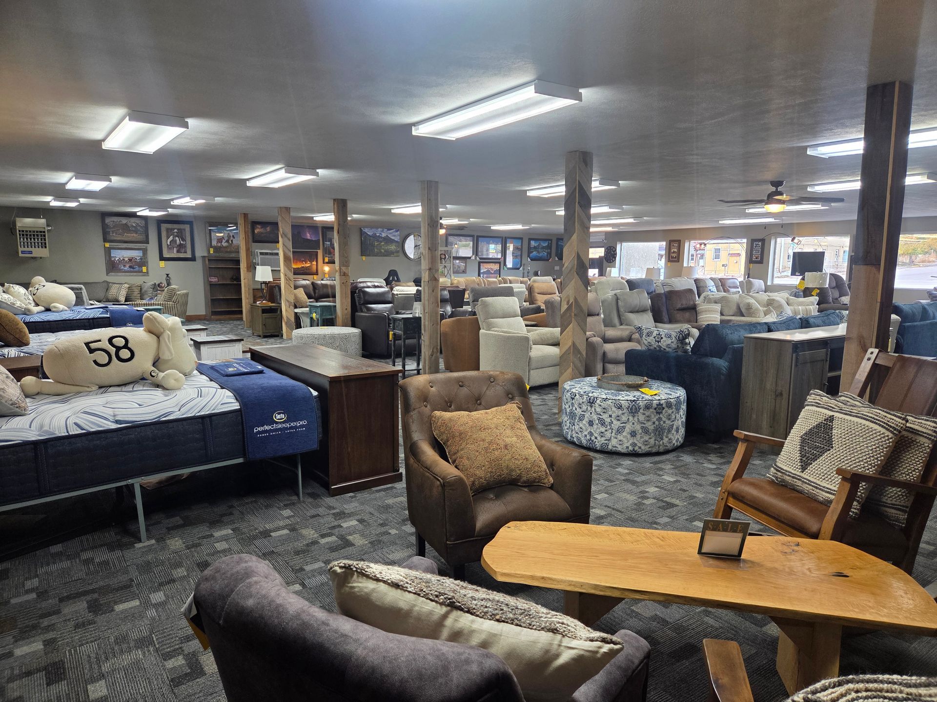 Interior of a furniture store with various sofas, chairs, and mattresses on display. Neutral color palette.