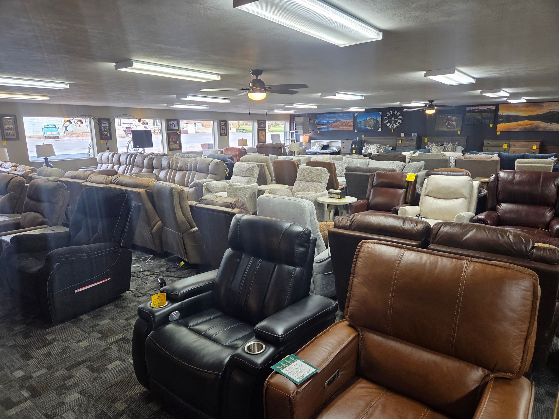 Furniture store interior with various sofas and recliners on display, well-lit.