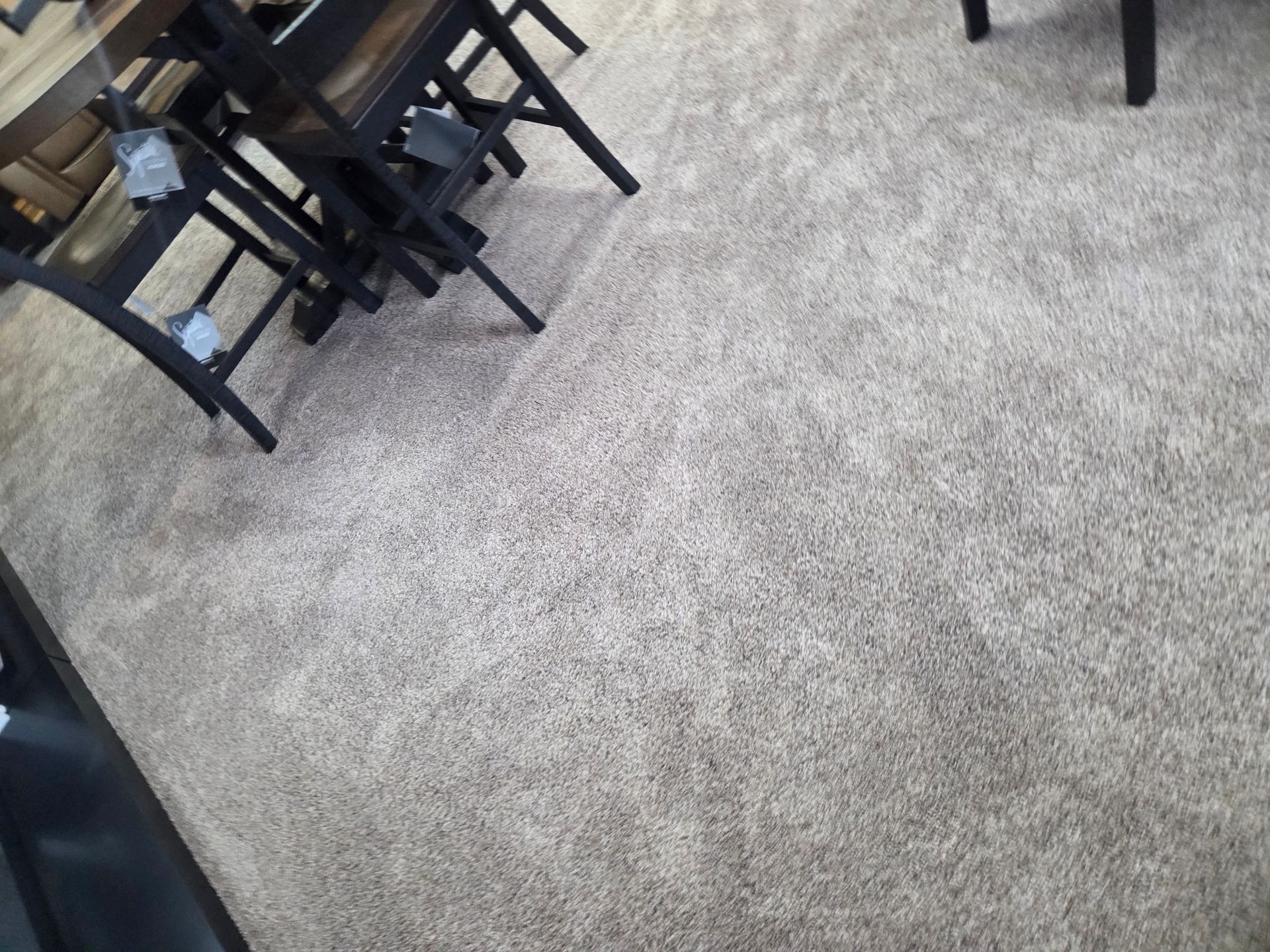 Beige carpet, with legs of wooden chairs and table partially visible in the corner.