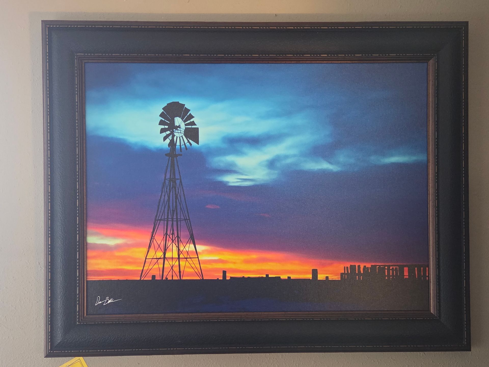 Windmill silhouette against a vibrant sunset with orange, purple, and blue hues.