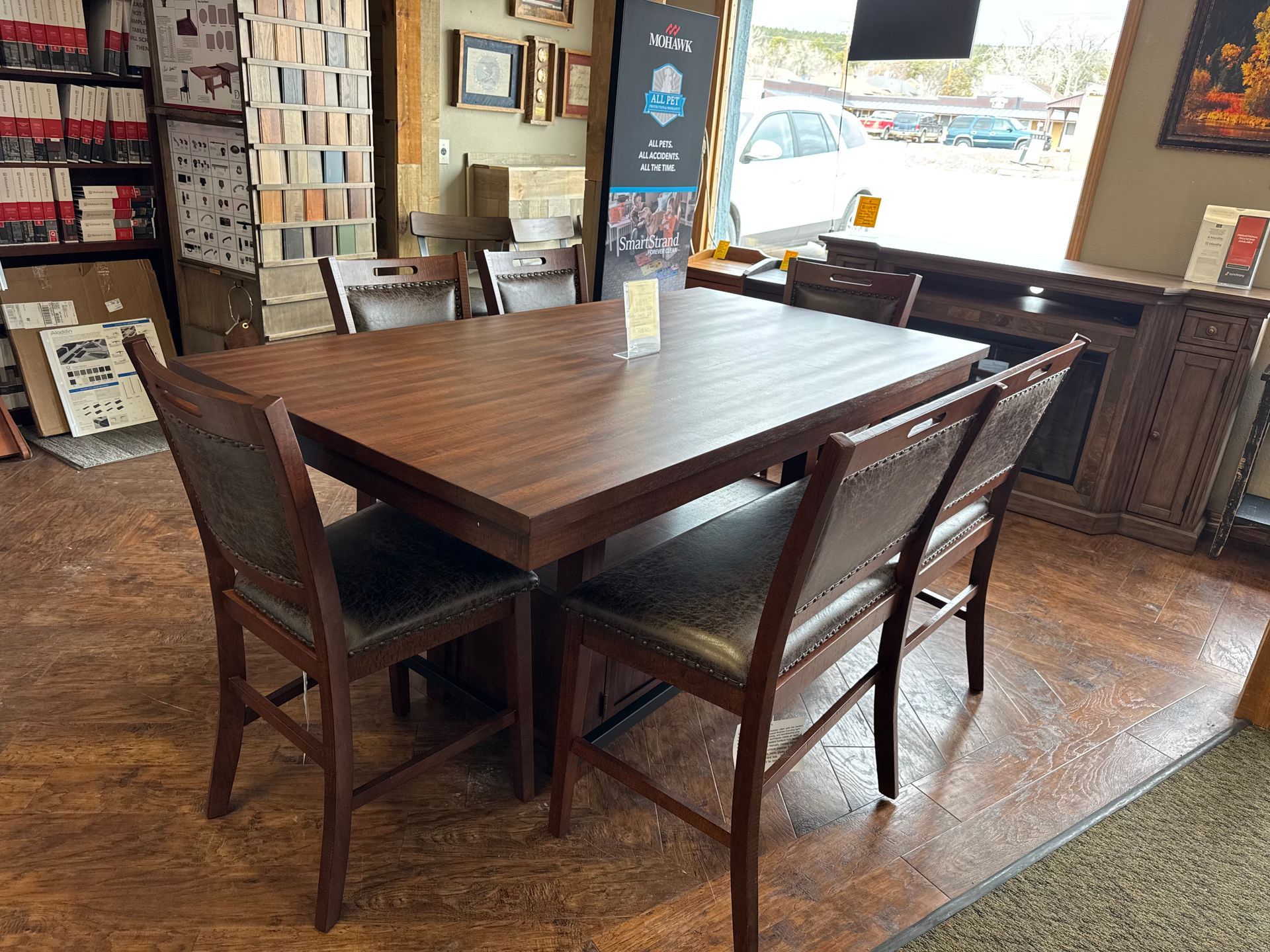 A dining set in a showroom: a dark wood table with four matching chairs.