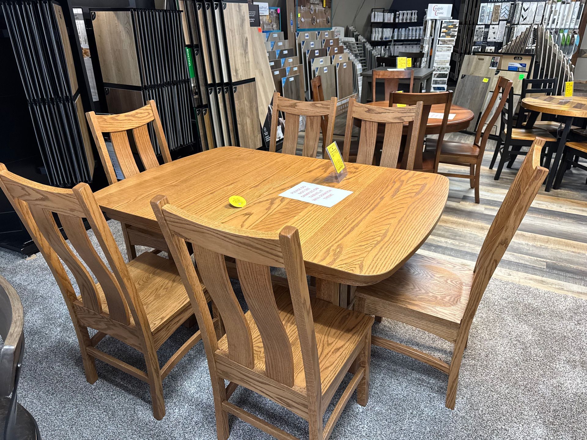 Wooden dining table with six matching chairs in a furniture store setting.