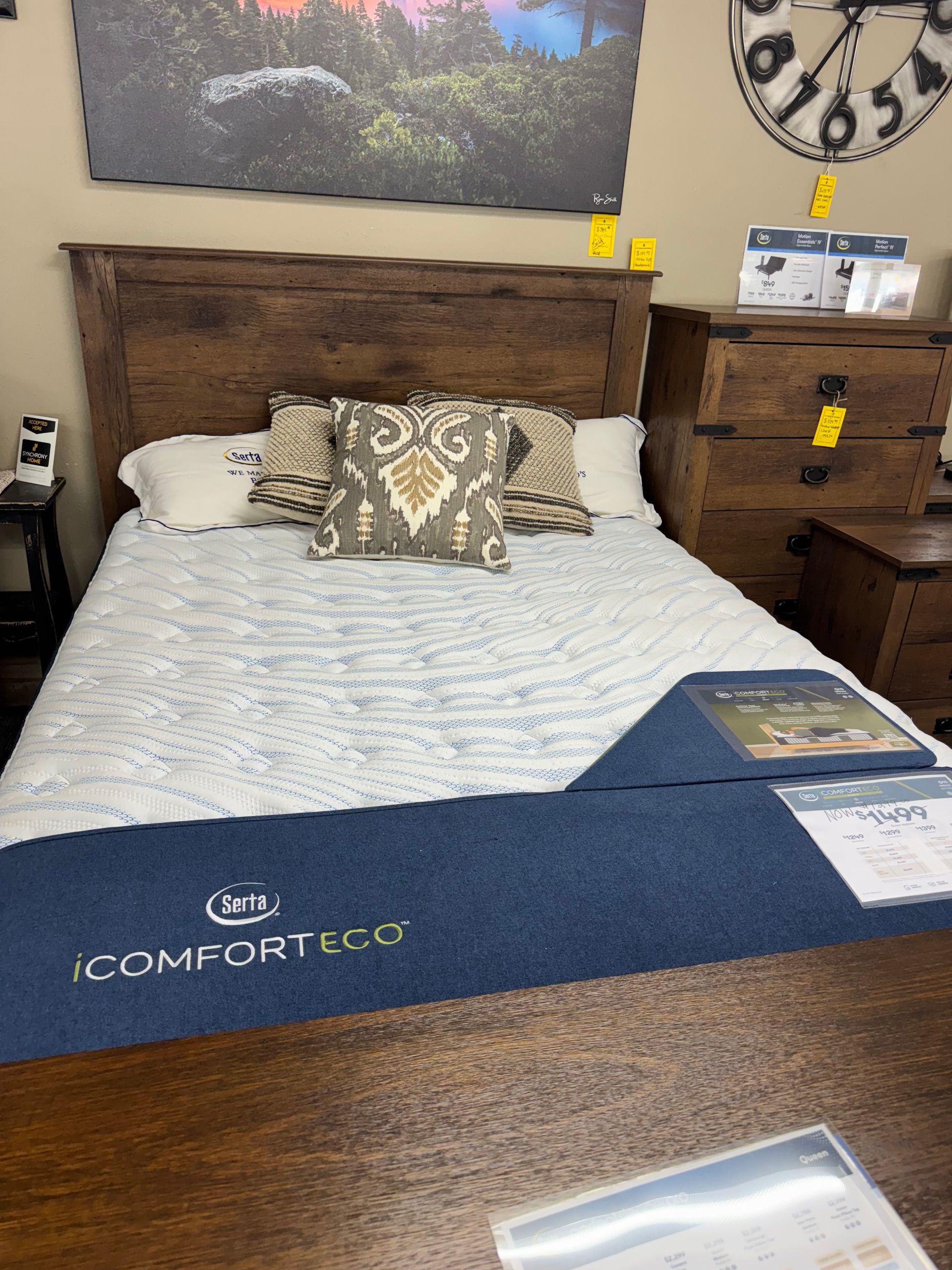 Wooden bed frame with mattress, pillows, and bedding. A dresser is on the right.