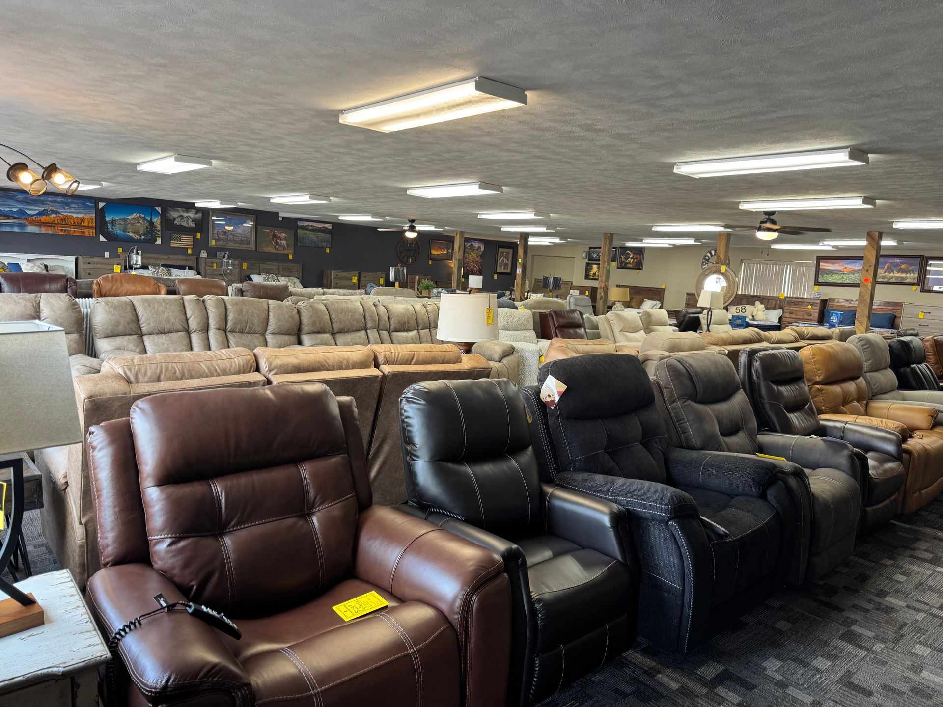A furniture store interior displays multiple reclining chairs in various colors and styles, with couches in the background.