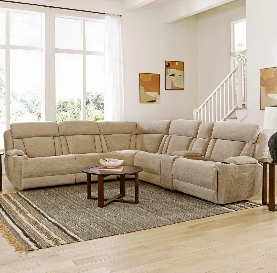 Beige sectional sofa in a living room with a round coffee table and a rug.