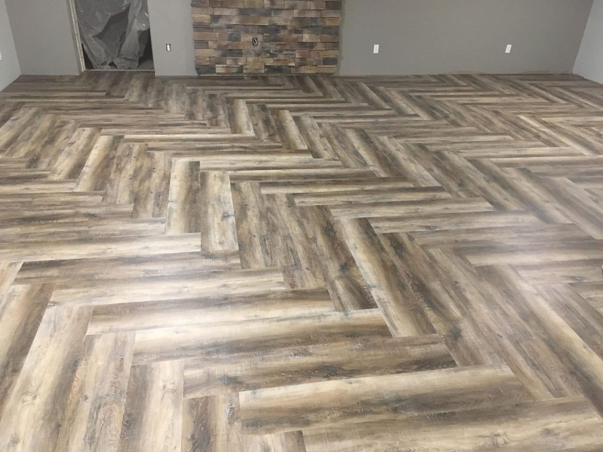 Herringbone pattern wood-look flooring, neutral tones, in a room.