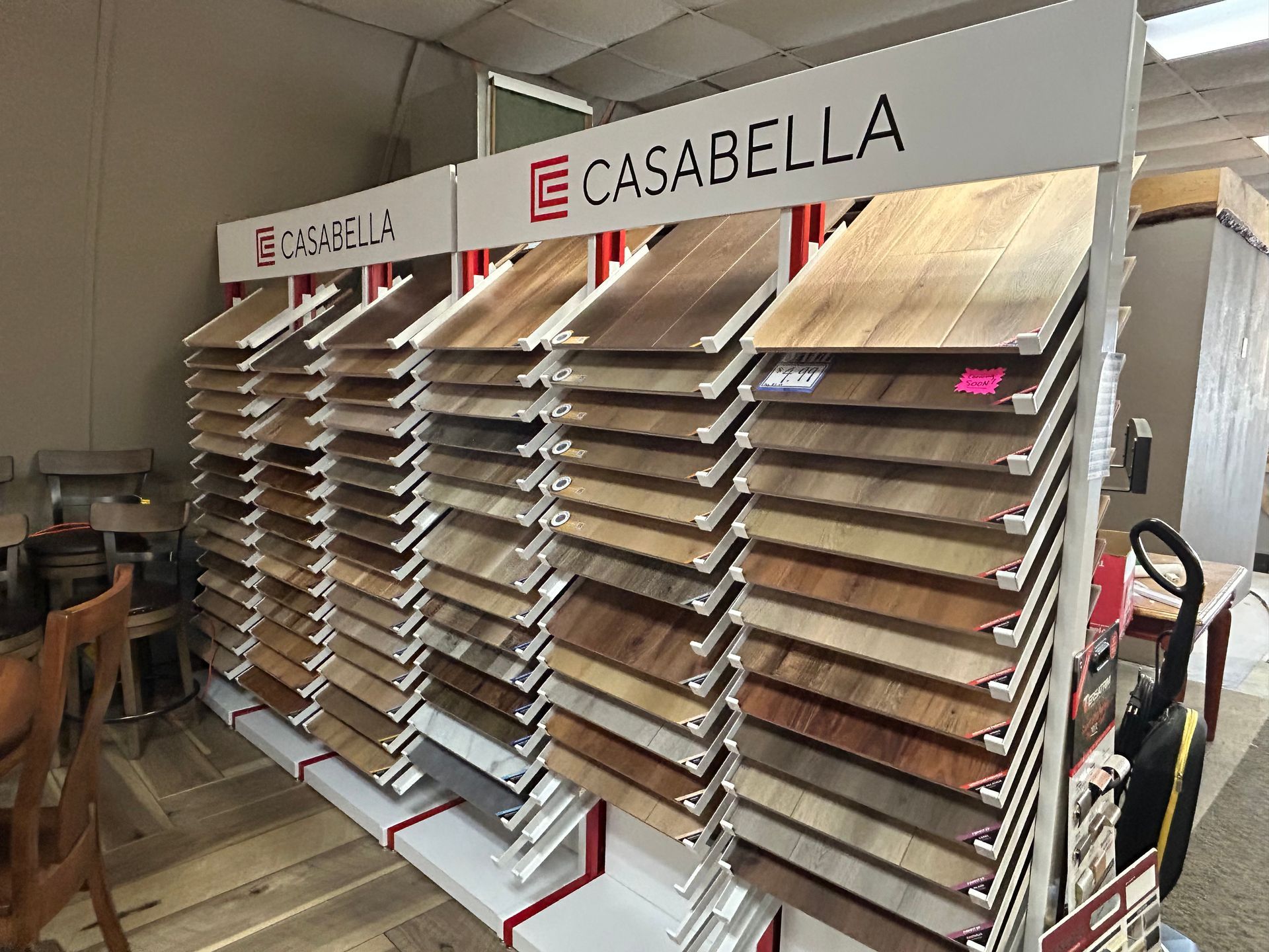 Display of Casabella flooring samples in a store; various wood-tone colors.