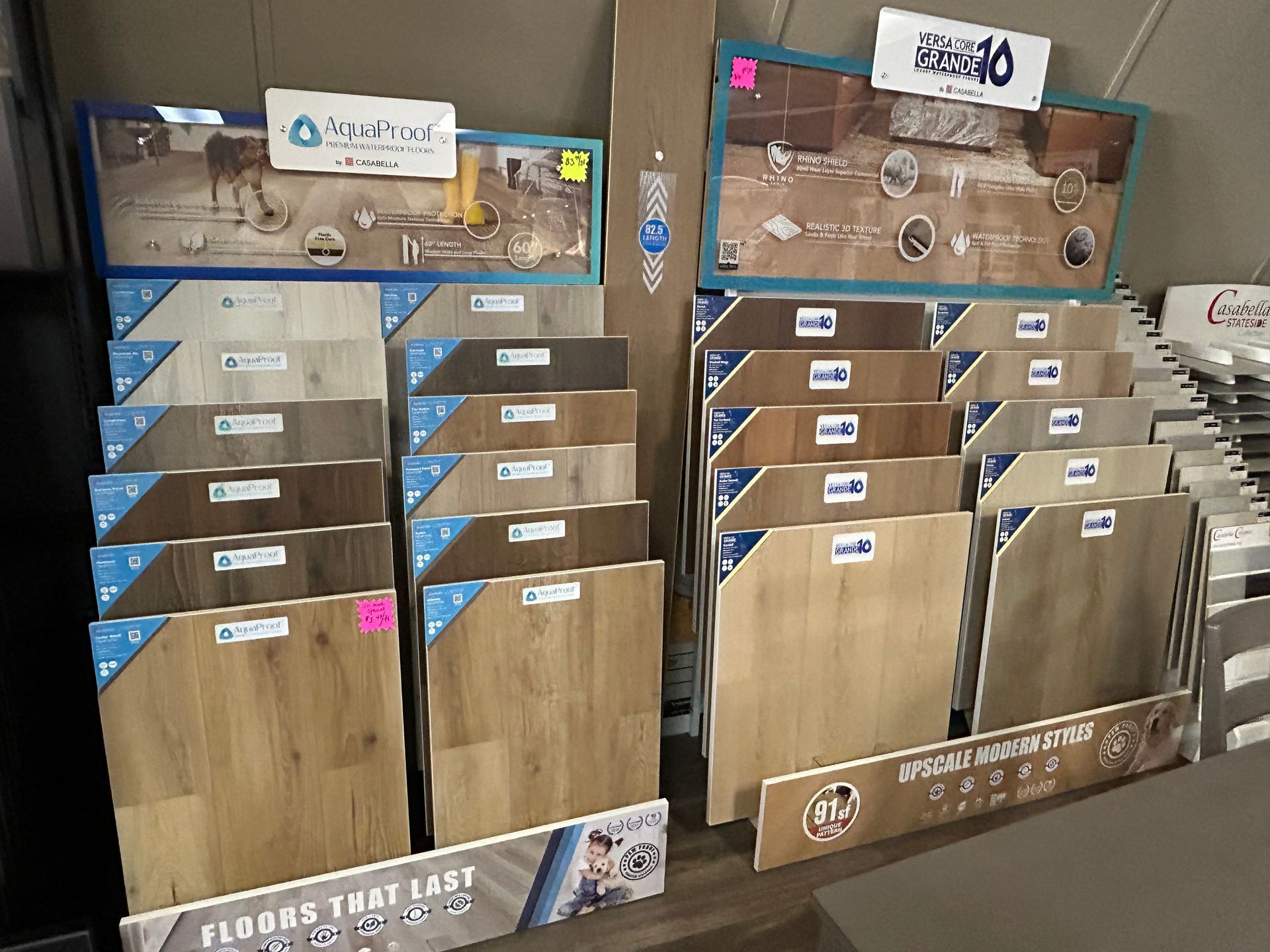 Flooring samples displayed in a store: various wood-look planks in light and medium tones.
