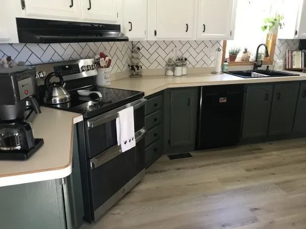 Kitchen with white upper cabinets, dark green lower cabinets, and a black oven.