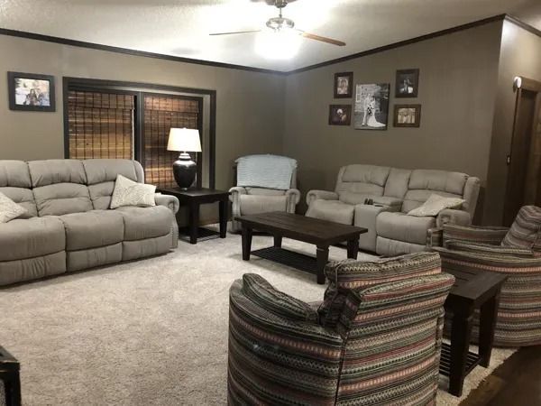 Living room with gray walls, beige carpet, and various furniture like sofas, chairs, and a coffee table.