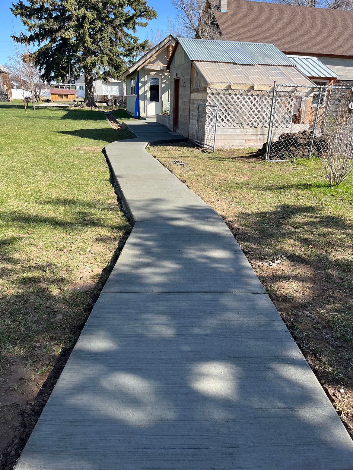 A concrete walkway leading to a house in the backyard.
