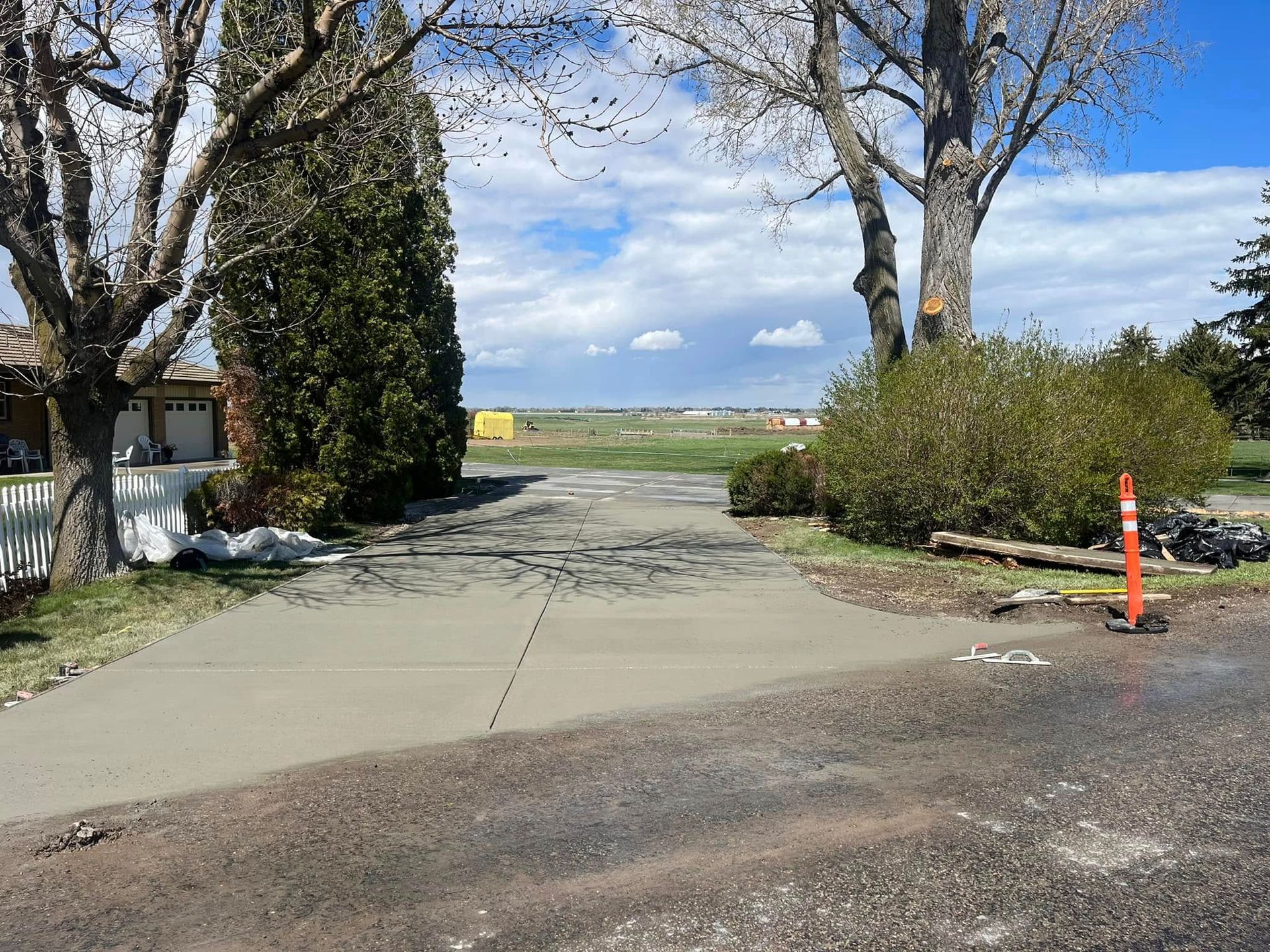 A concrete driveway leading to a house with trees on both sides