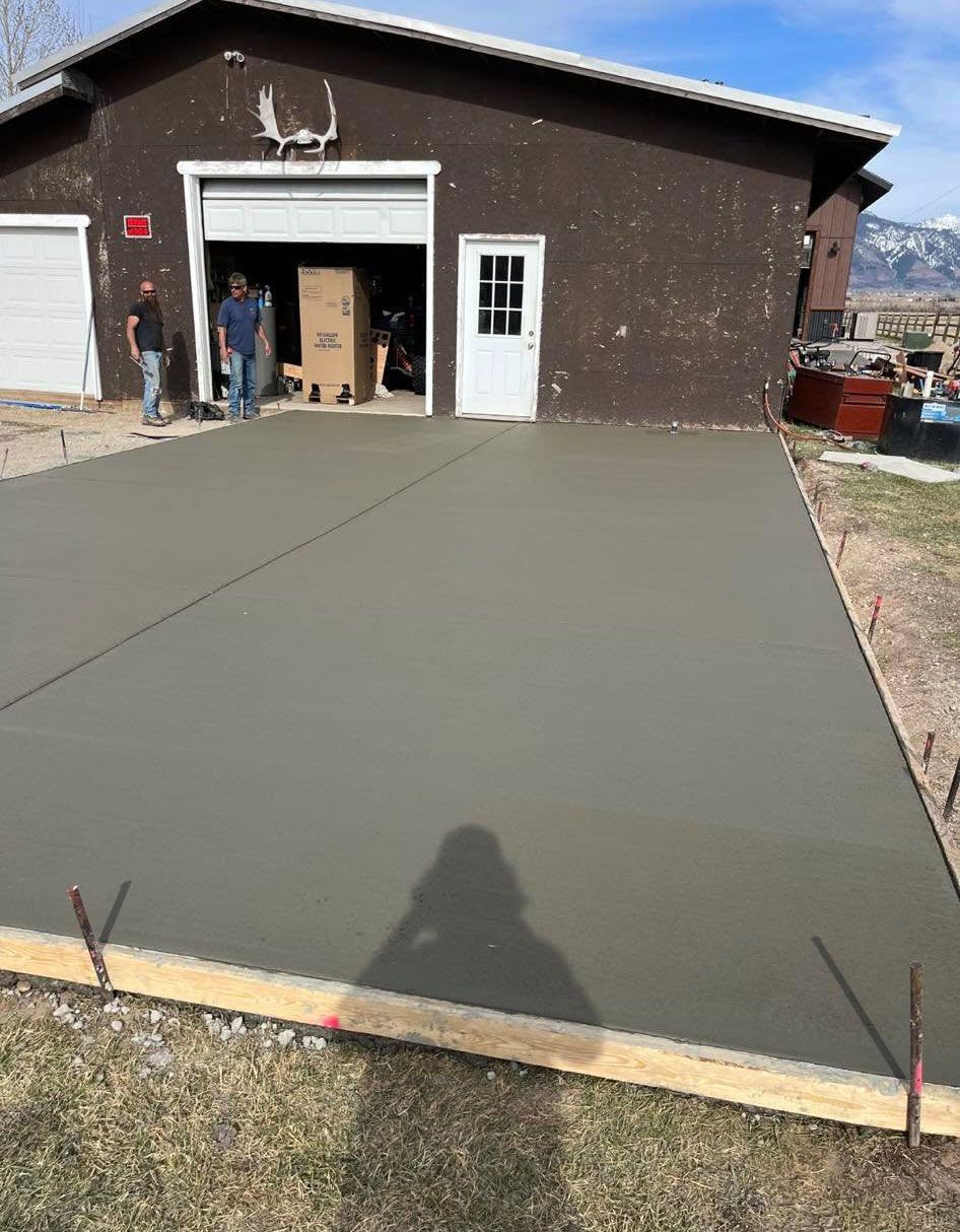 A concrete driveway is being built in front of a garage