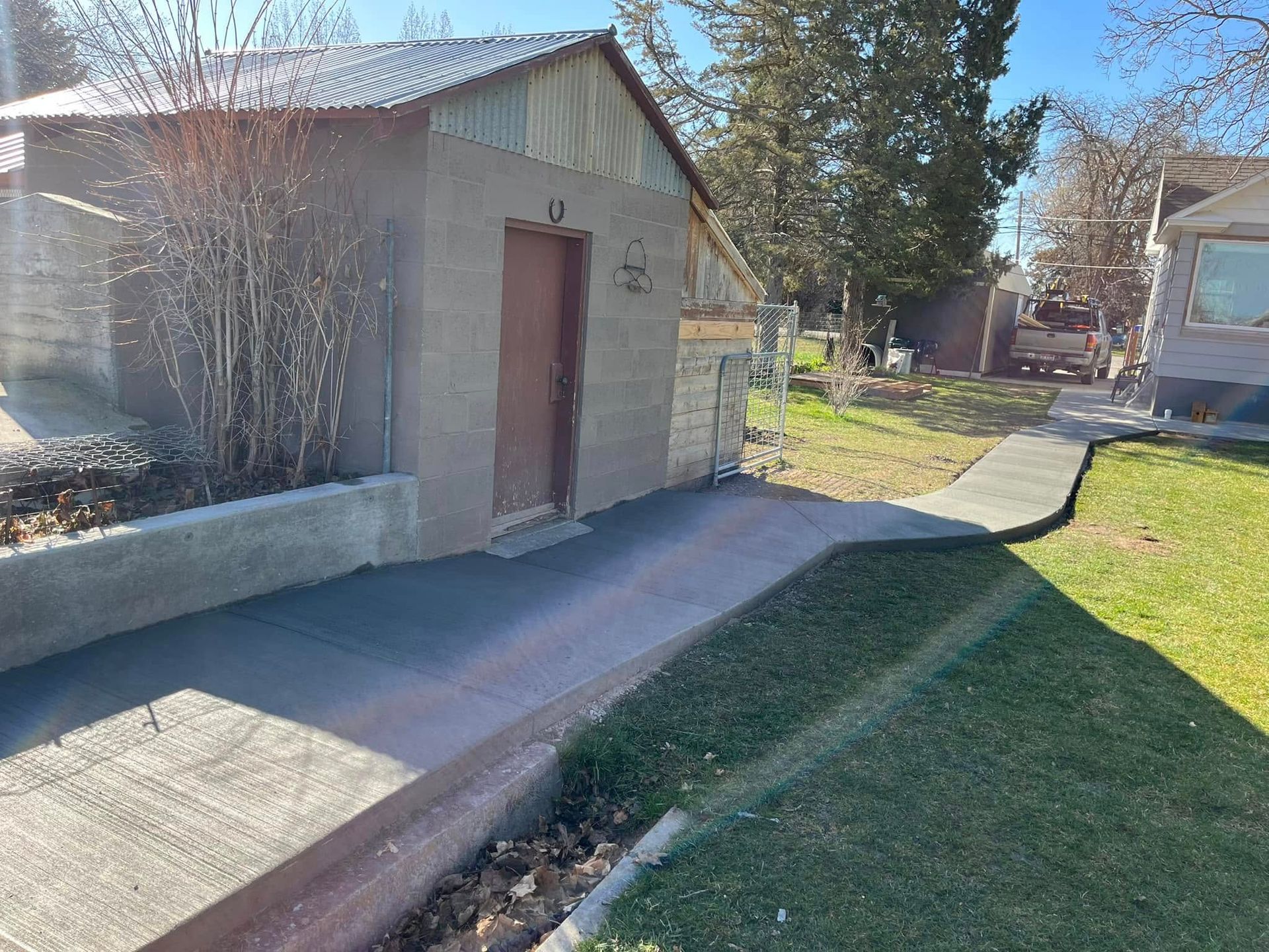 There is a concrete walkway leading to a shed in the backyard