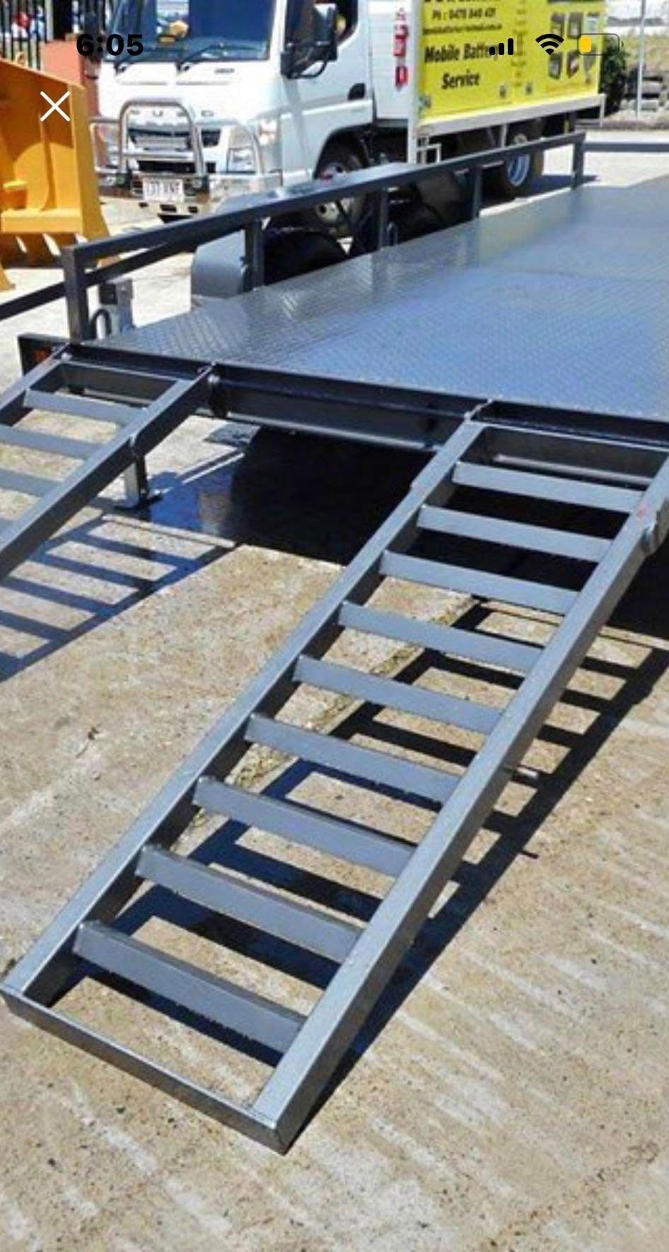 A yellow truck is parked next to a metal ramp