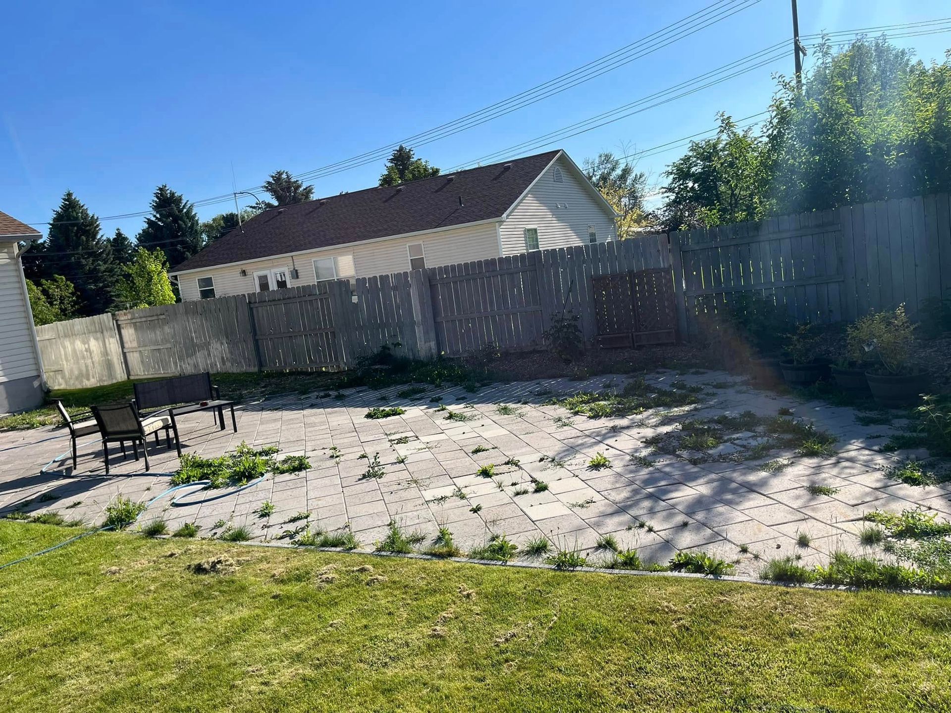 A backyard with a fence , chairs , and a house in the background