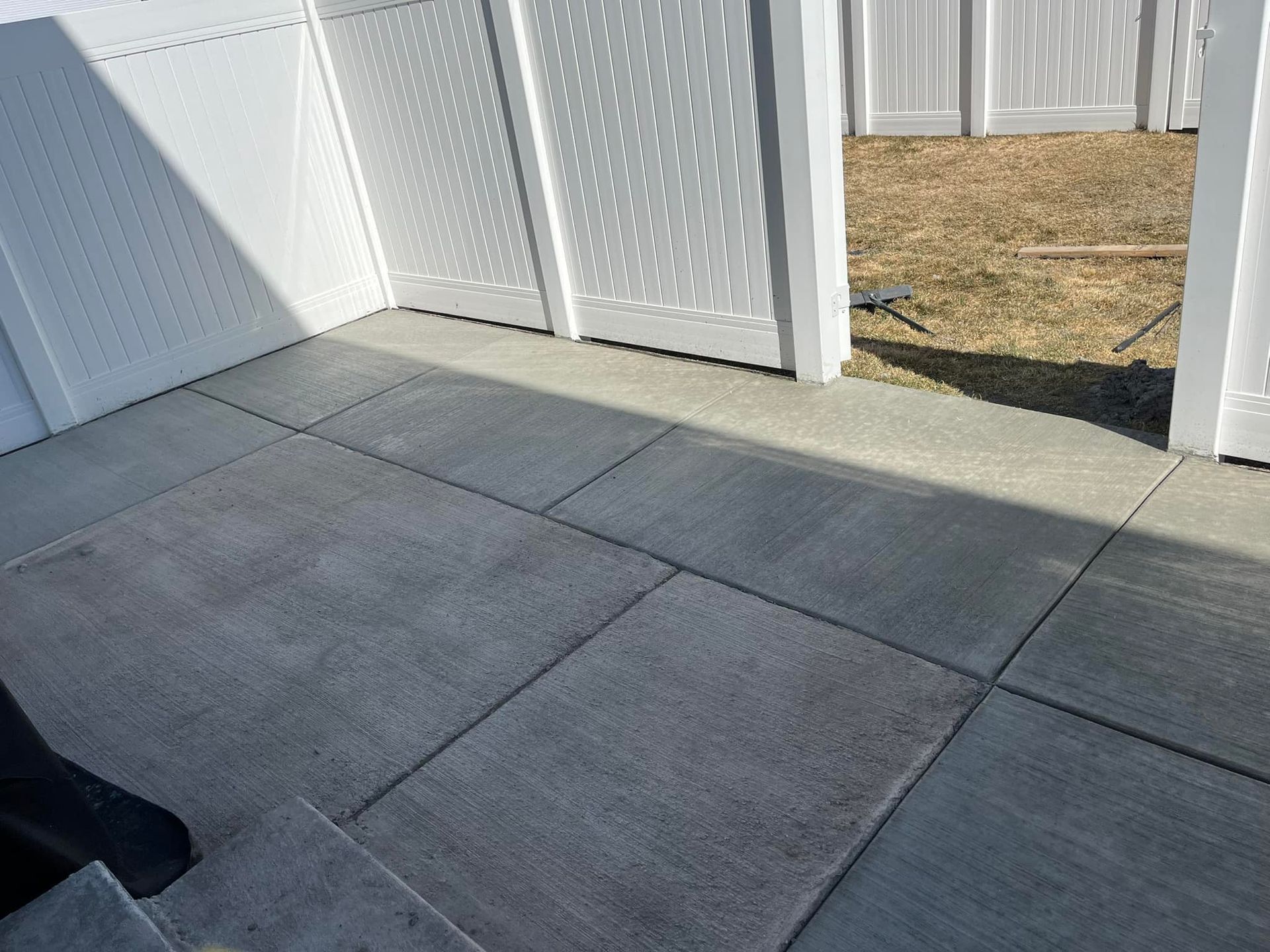 A concrete floor with a white fence in the background