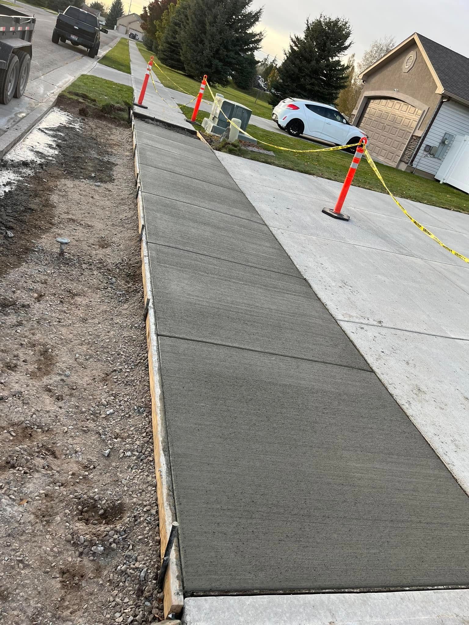 A concrete sidewalk is being built on the side of a road