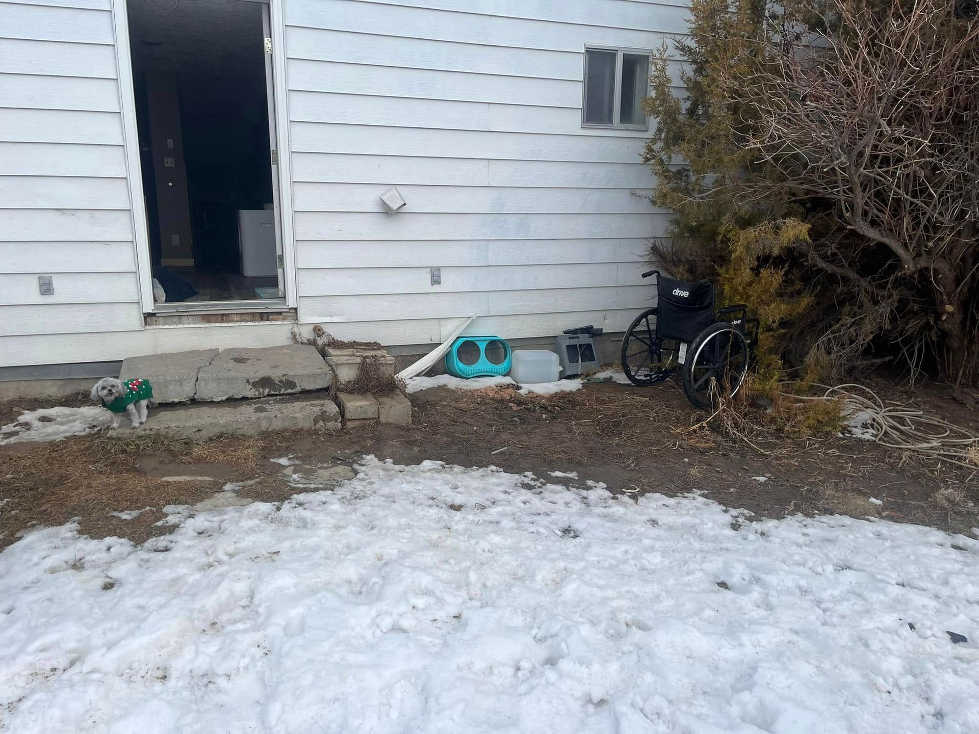 A wheelchair is parked in front of a house in the snow