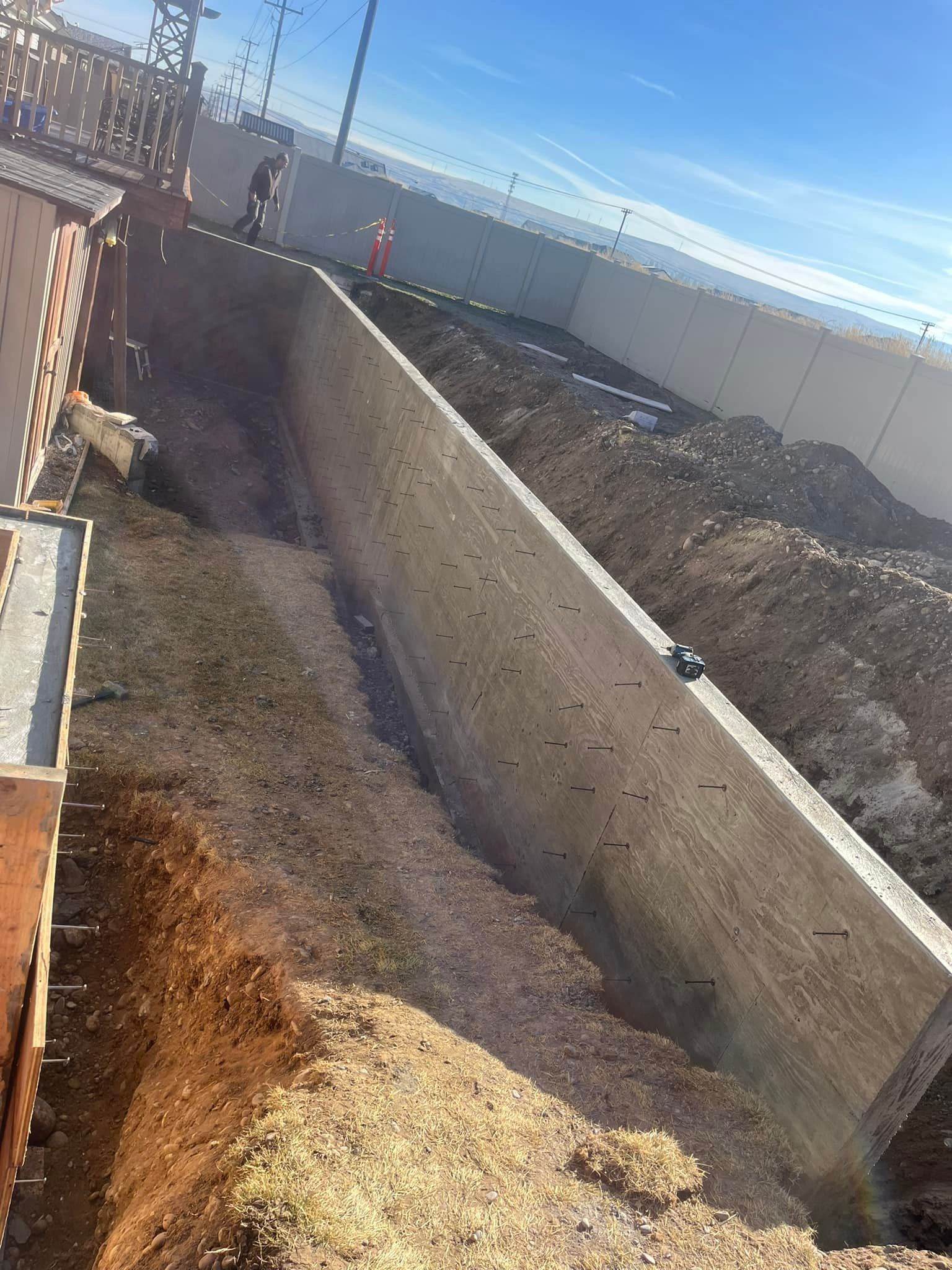 A large concrete wall is being built on top of a dirt field
