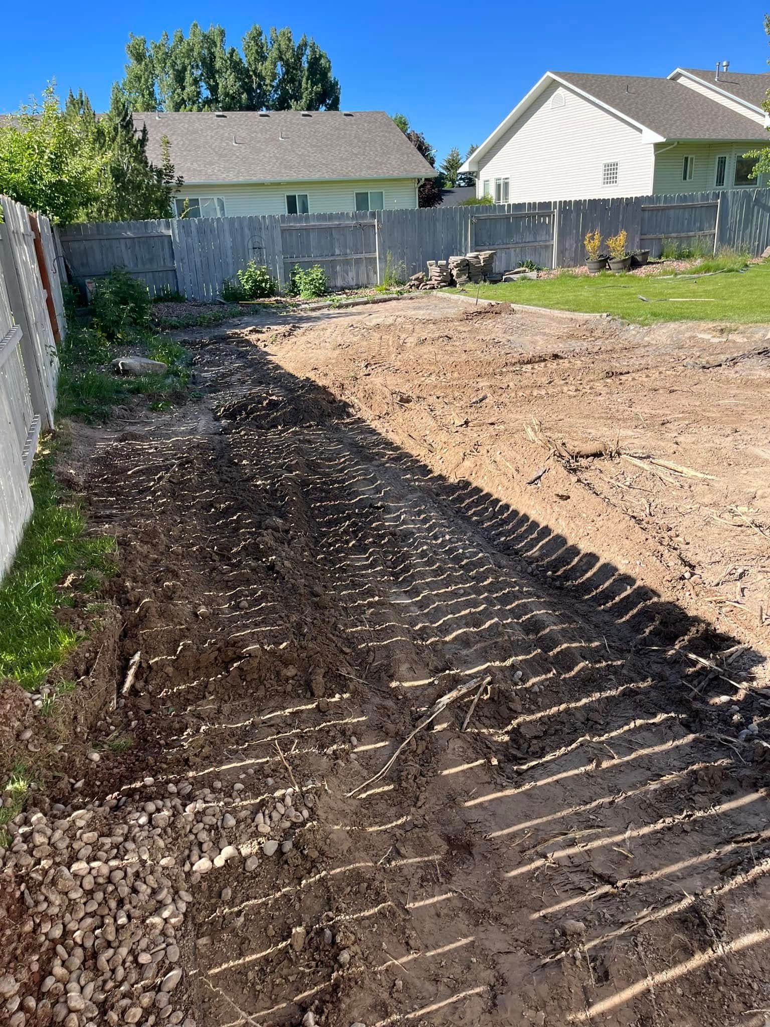 A dirt road leading to a house with a fence in the background