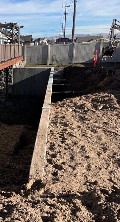 A concrete wall is being built next to a pile of dirt.