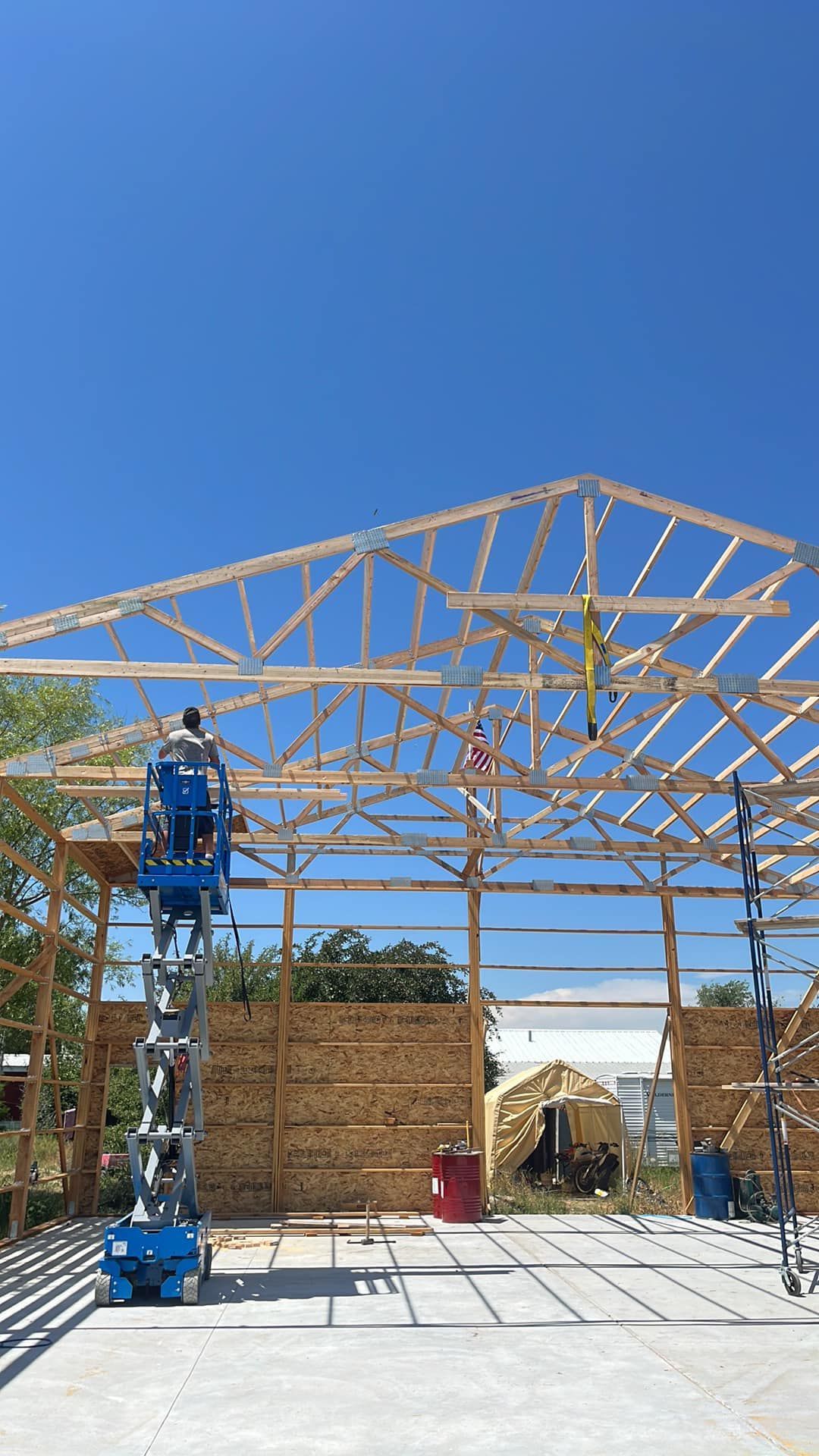 A man is standing on a scissor lift in front of a building under construction