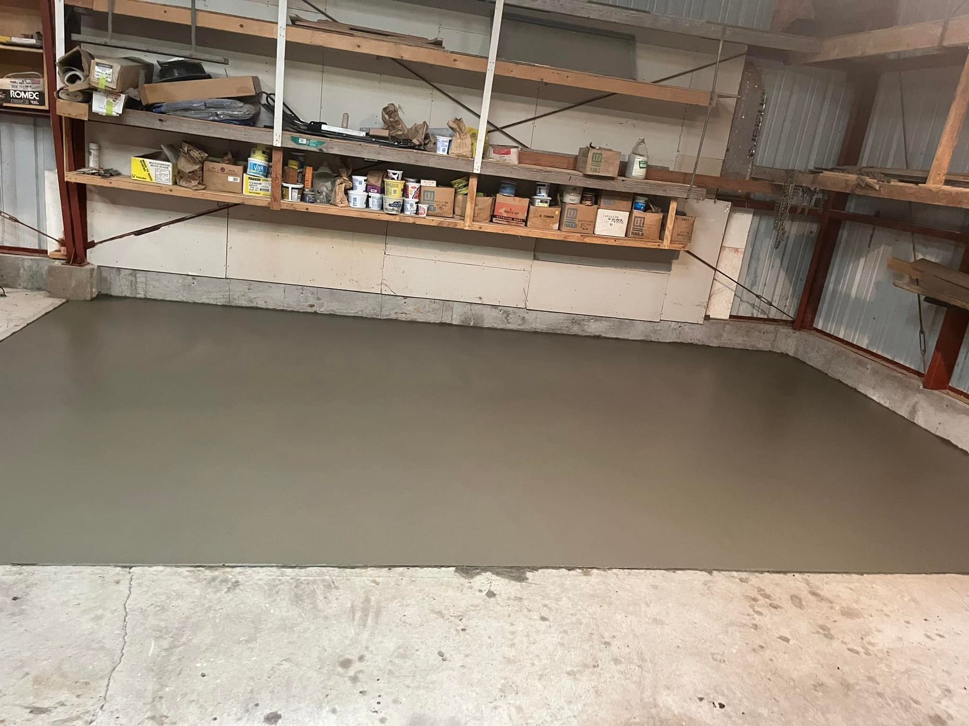 A concrete floor in a garage with shelves filled with boxes