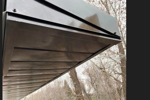 A close up of a metal roof with trees in the background
