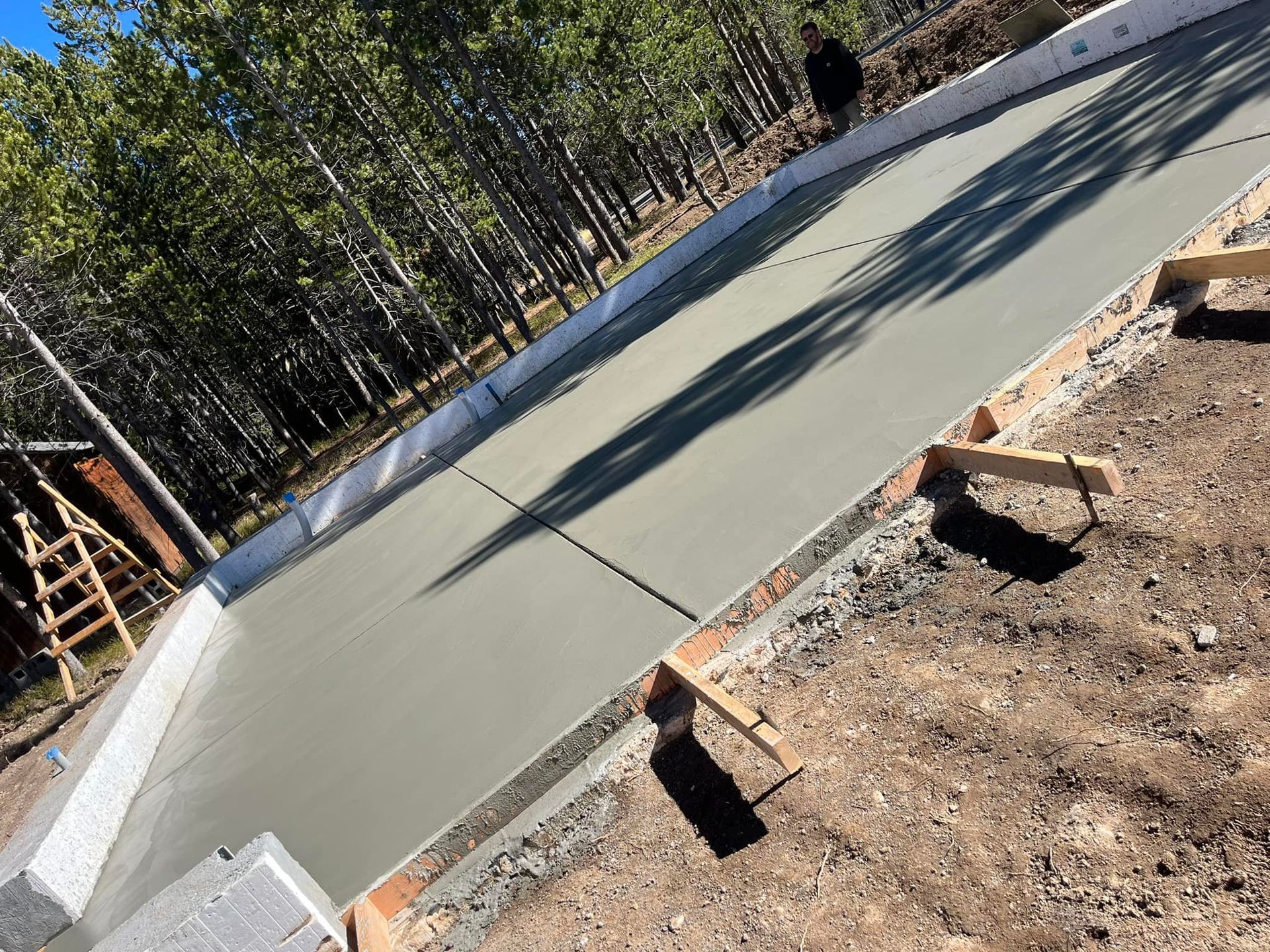 A concrete driveway is being built in the middle of a forest