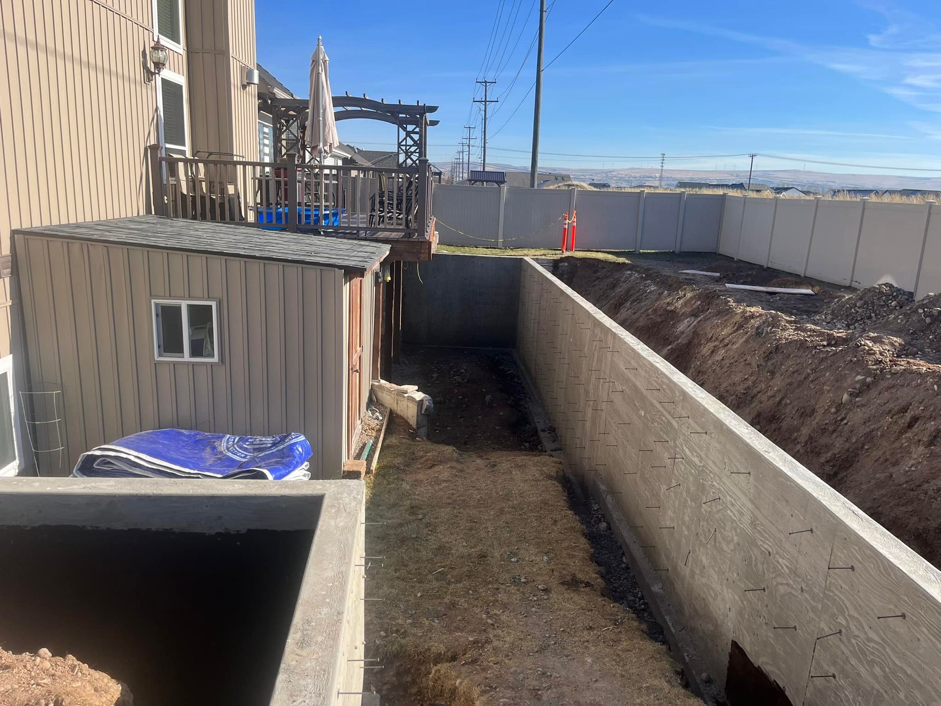 A concrete wall is being built in the backyard of a house