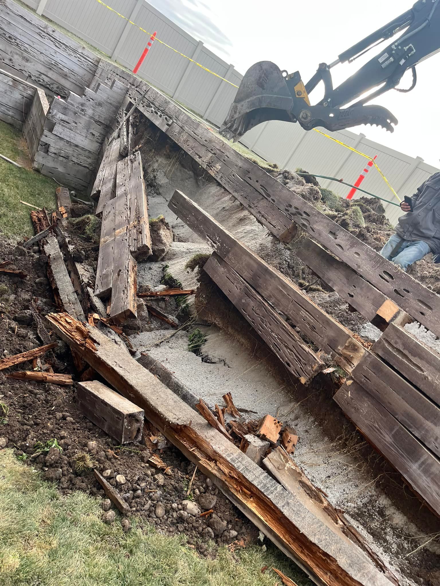 A large piece of wood is laying on the ground next to a crane