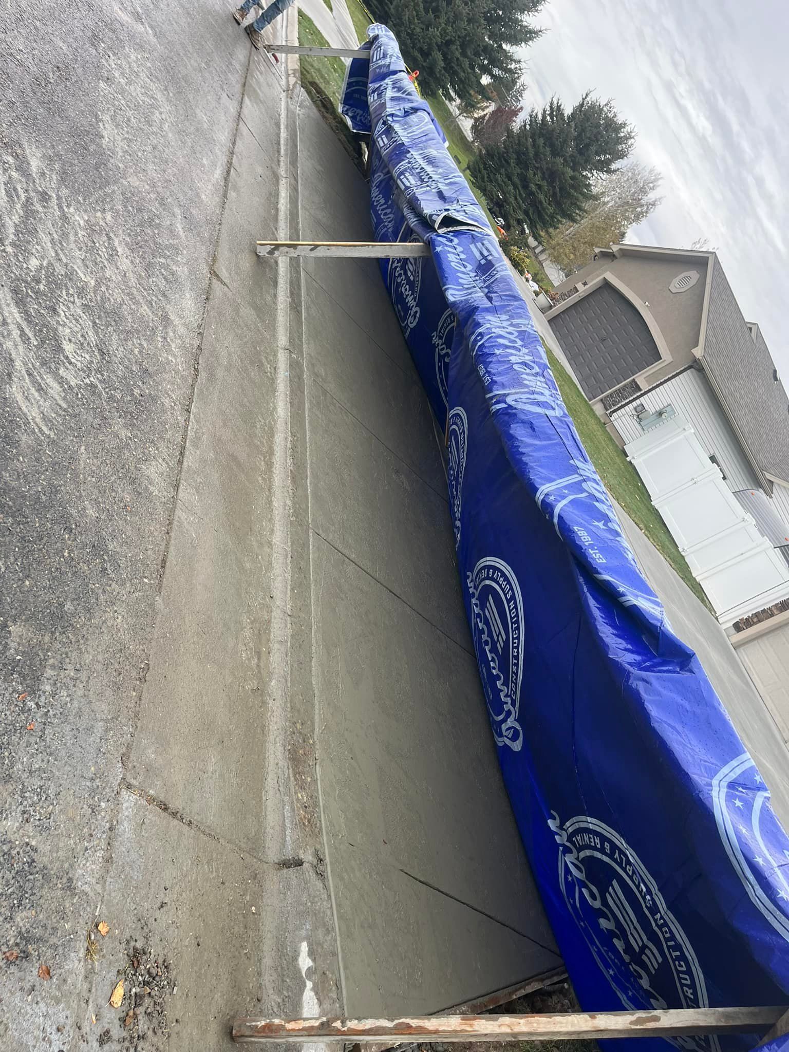 A blue tarp is sitting on the sidewalk next to a house