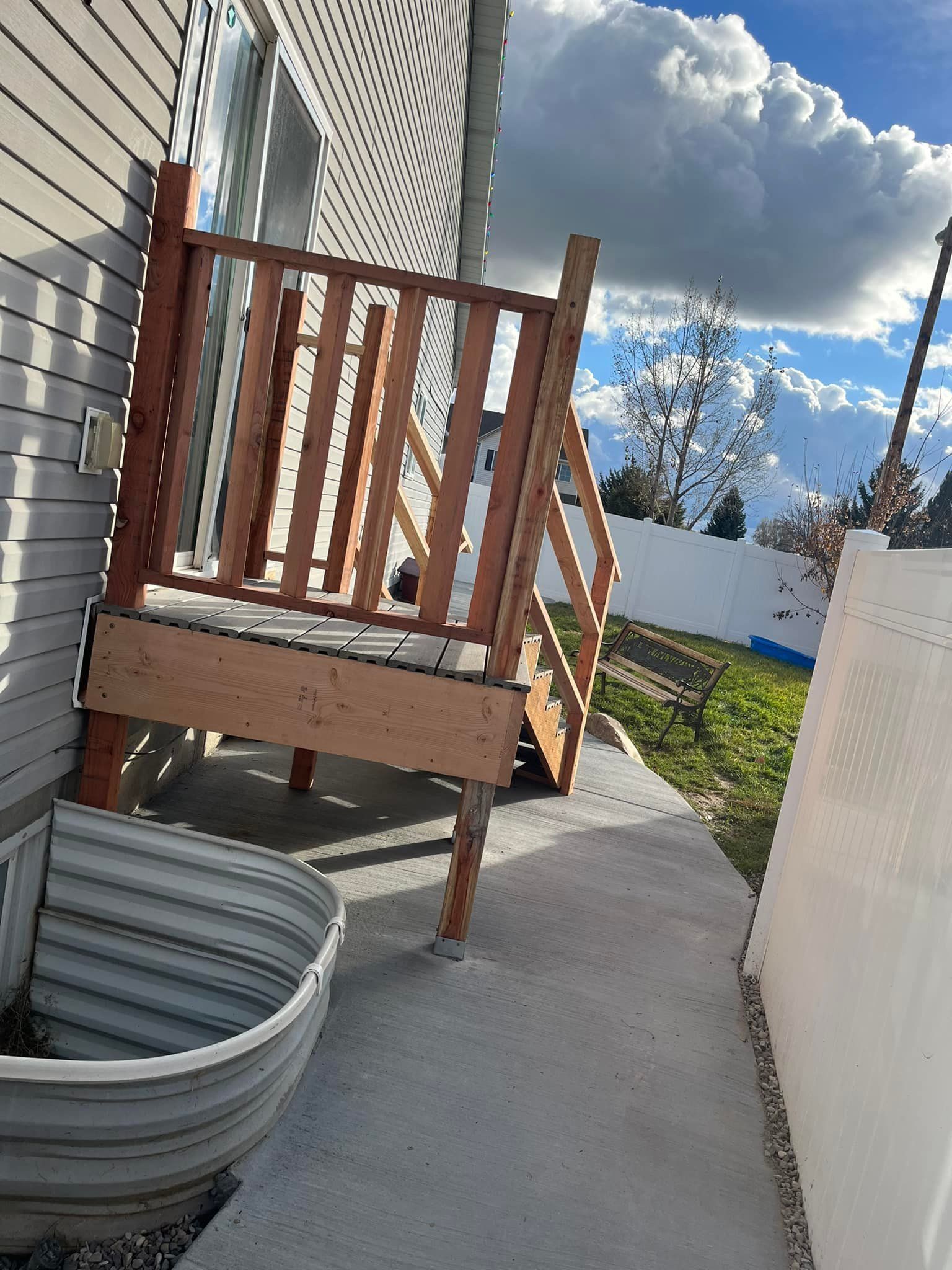 A wooden deck is sitting on the side of a house next to a window
