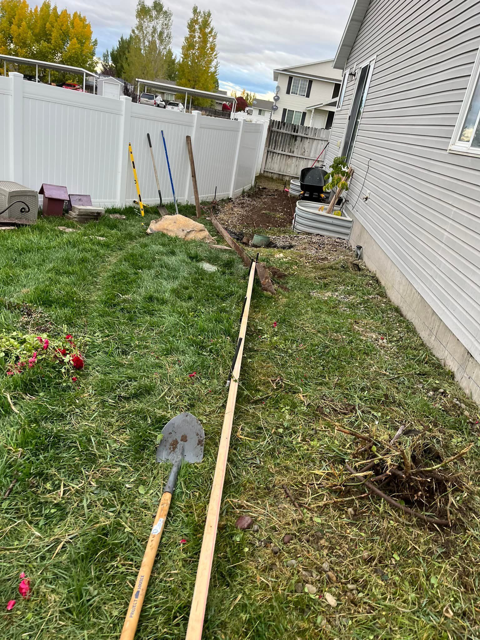 A shovel and rake are sitting in the grass in front of a house