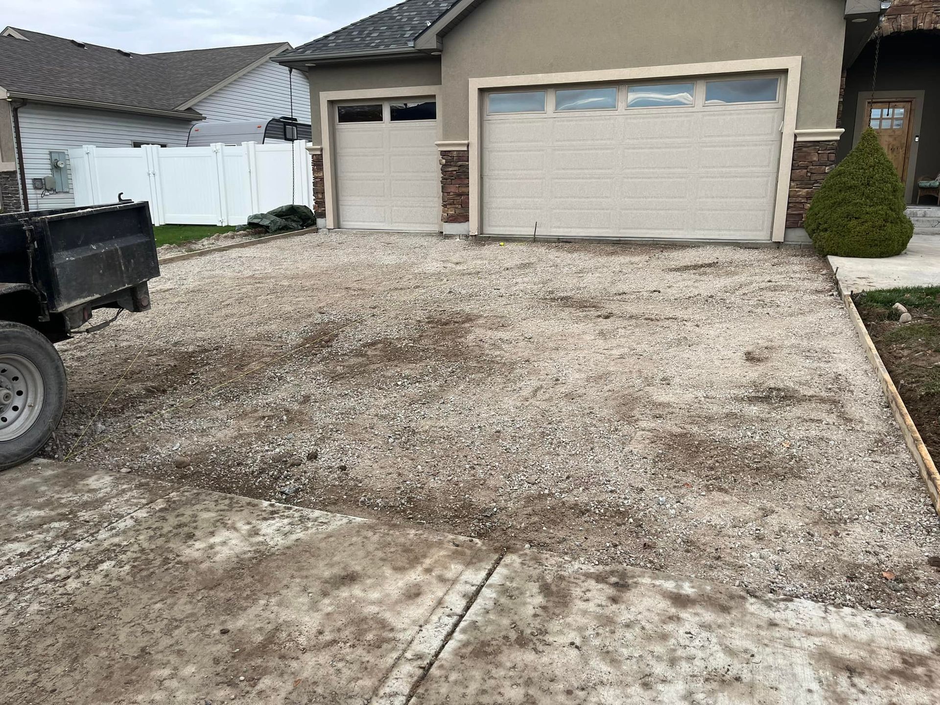 A truck is parked in a dirt driveway in front of a house